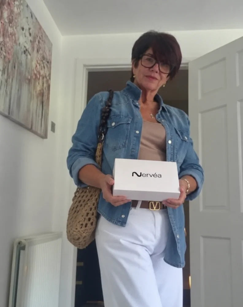 Femme en veste bleue tenant une boîte Nervéa.